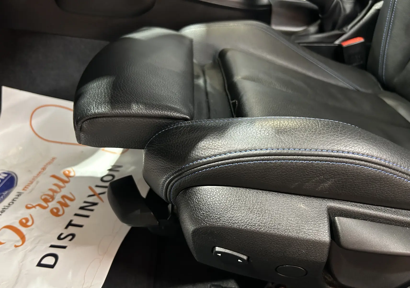 Gros plan sur le siège avant en cuir noir avec surpiqûres bleues de la BMW Série 1 120iA M Sport blanche.