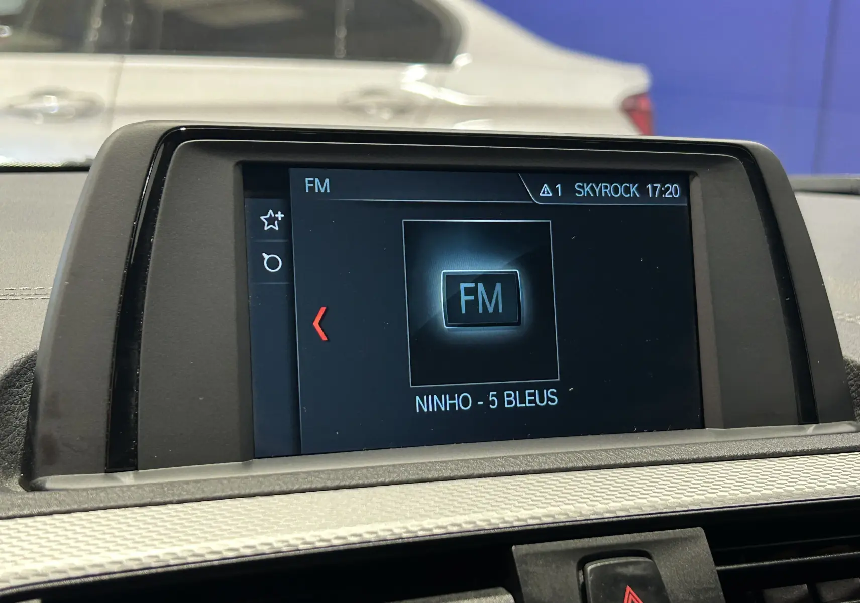 Écran central de la BMW Série 1 120iA M Sport blanc affichant la radio FM sur fond intérieur clair.