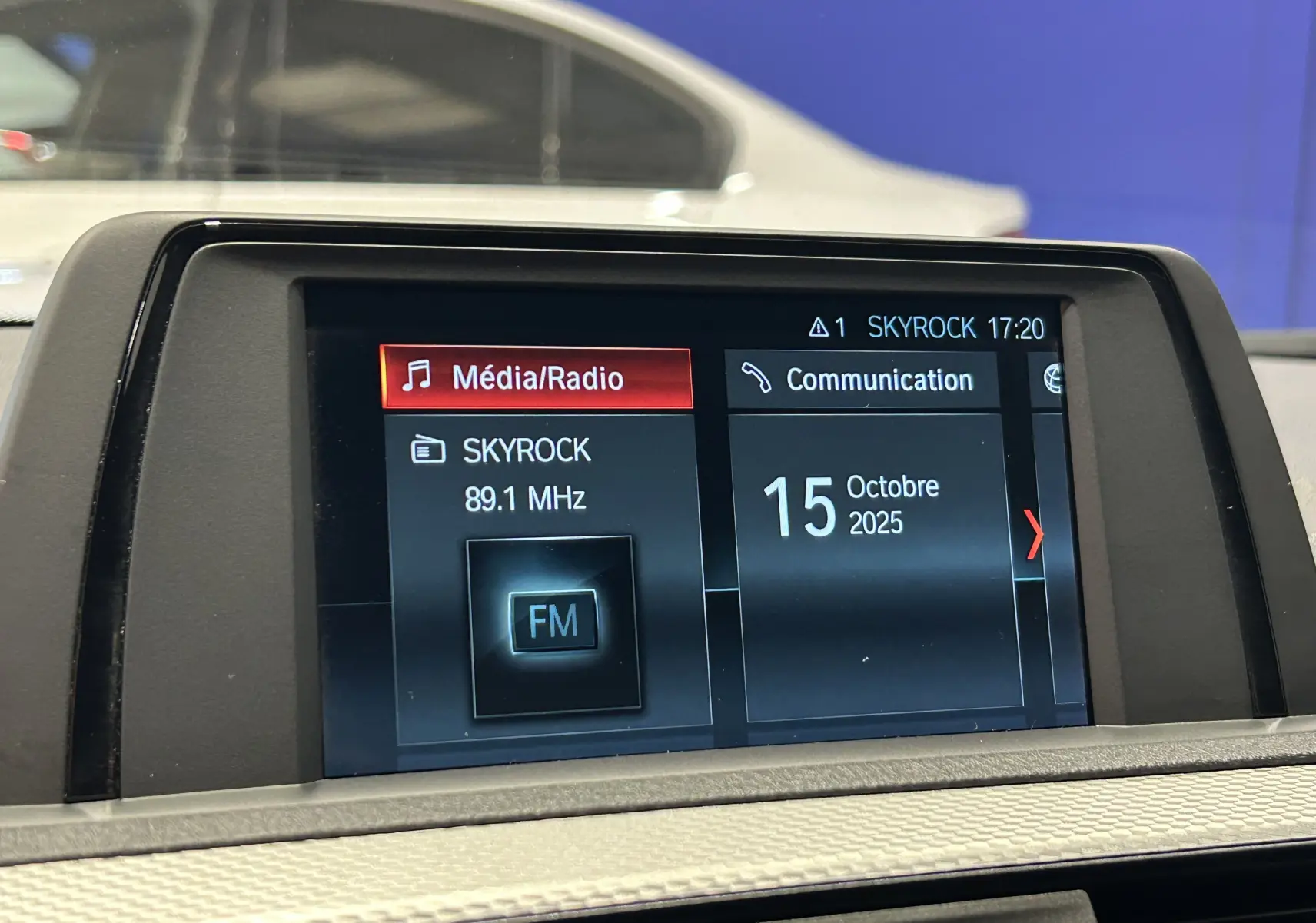 Écran central de la BMW Série 1 120iA blanc affichant la radio Skyrock et la date du 15 octobre 2025.