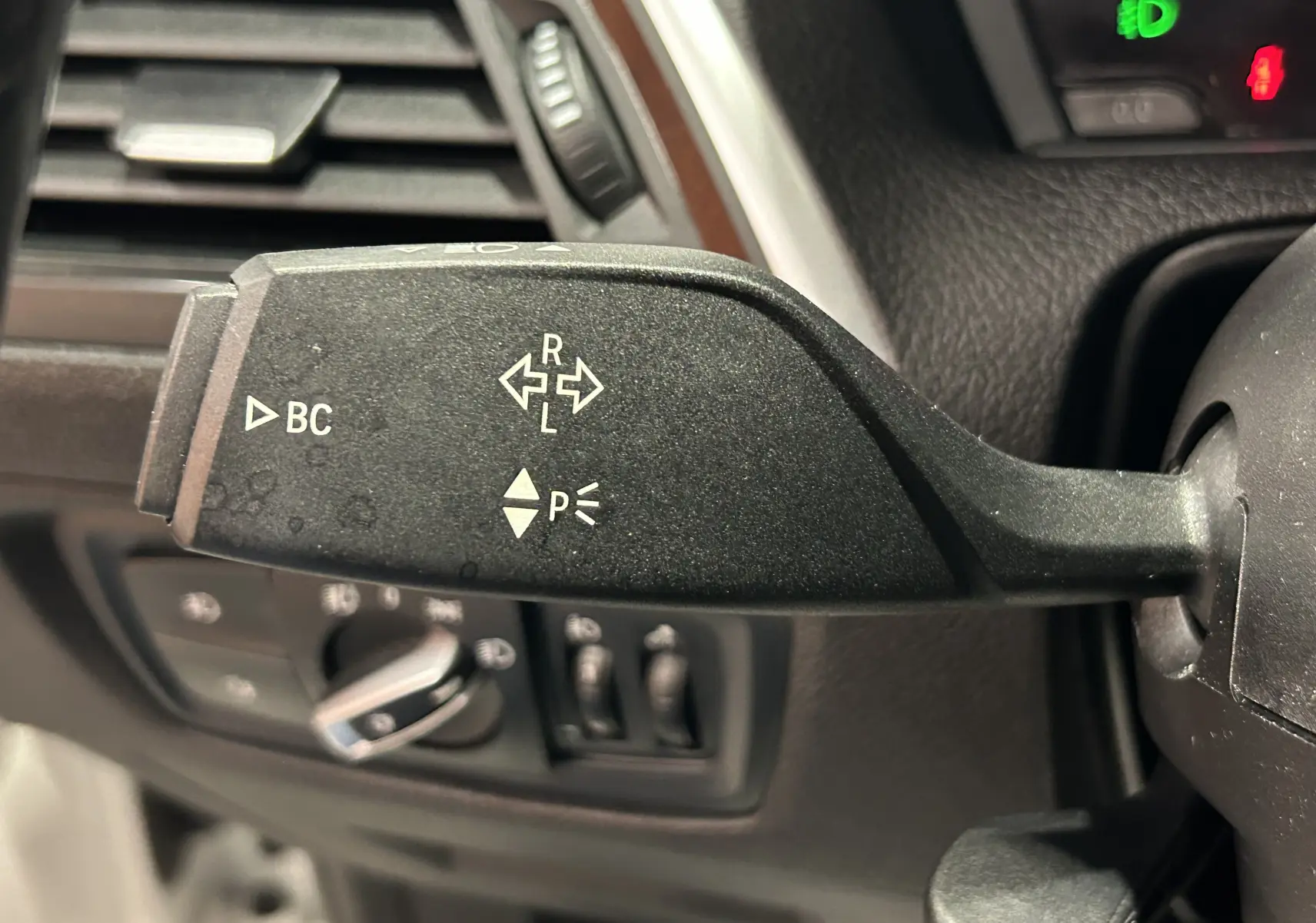 Gros plan sur la manette de clignotant gauche de la BMW Série 1 120iA M Sport blanche, montrant les commandes BC et clignotants.