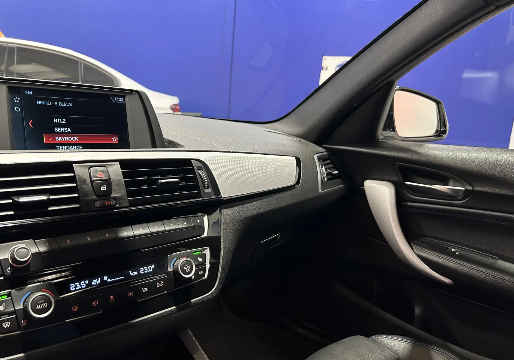 Vue intérieure côté passager de la BMW Série 1 120iA M Sport 2019, tableau de bord et console noire avec écran multimédia.