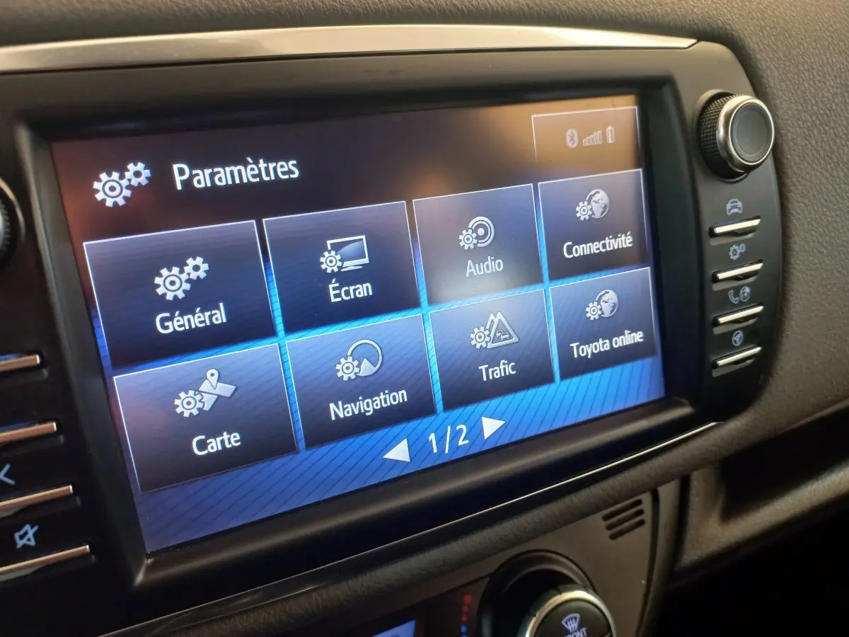 Écran tactile central de la Toyota Yaris hybride 2018 affichant le menu des paramètres en intérieur noir.