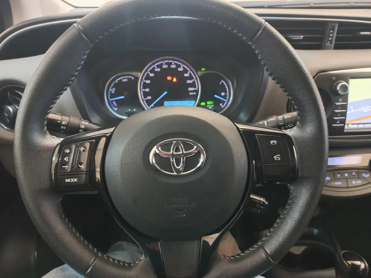 Vue rapprochée du volant en cuir noir de la Toyota Yaris 2018 avec tableau de bord et écran tactile visibles.