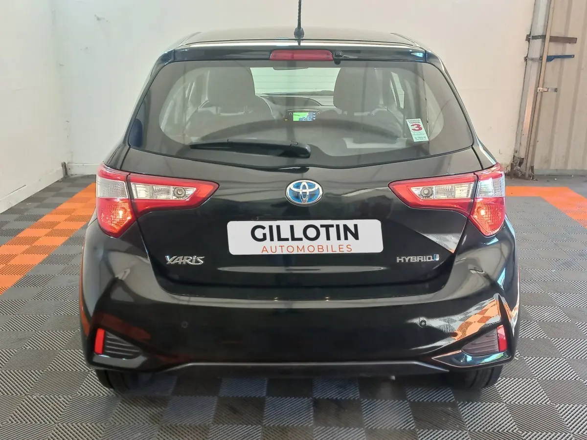 Vue arrière d'une Toyota Yaris noire hybride 2018 avec feux arrière distinctifs et logo Toyota visible.