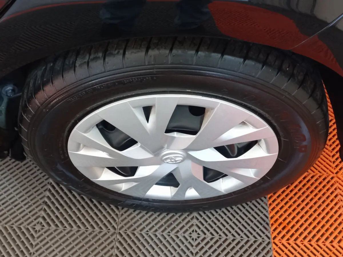 Gros plan sur la roue avant droite de la Toyota Yaris noire, mettant en valeur la jante argentée au design moderne.