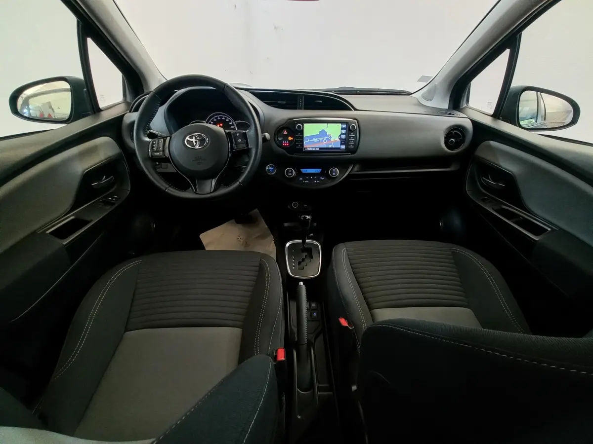 Vue intérieure avant de la Toyota Yaris noire 2018, montrant le tableau de bord avec écran tactile et volant multifonctions cuir.