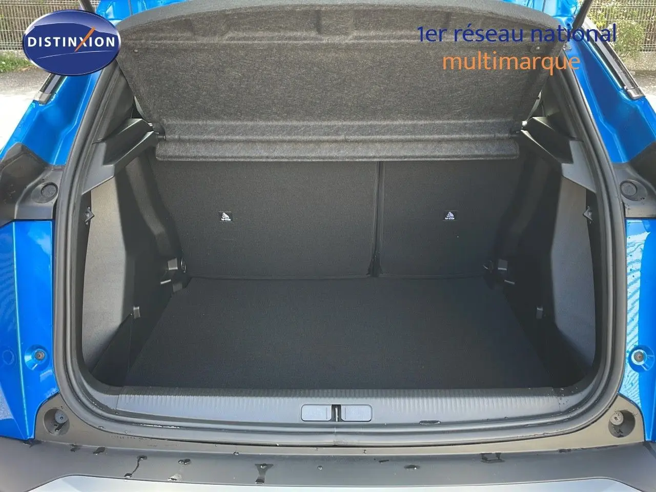 Coffre ouvert vu de l'arrière d'une Peugeot 2008 1.2 PureTech 100ch bleu Vertigo Métal, montrant l'espace de chargement vide.