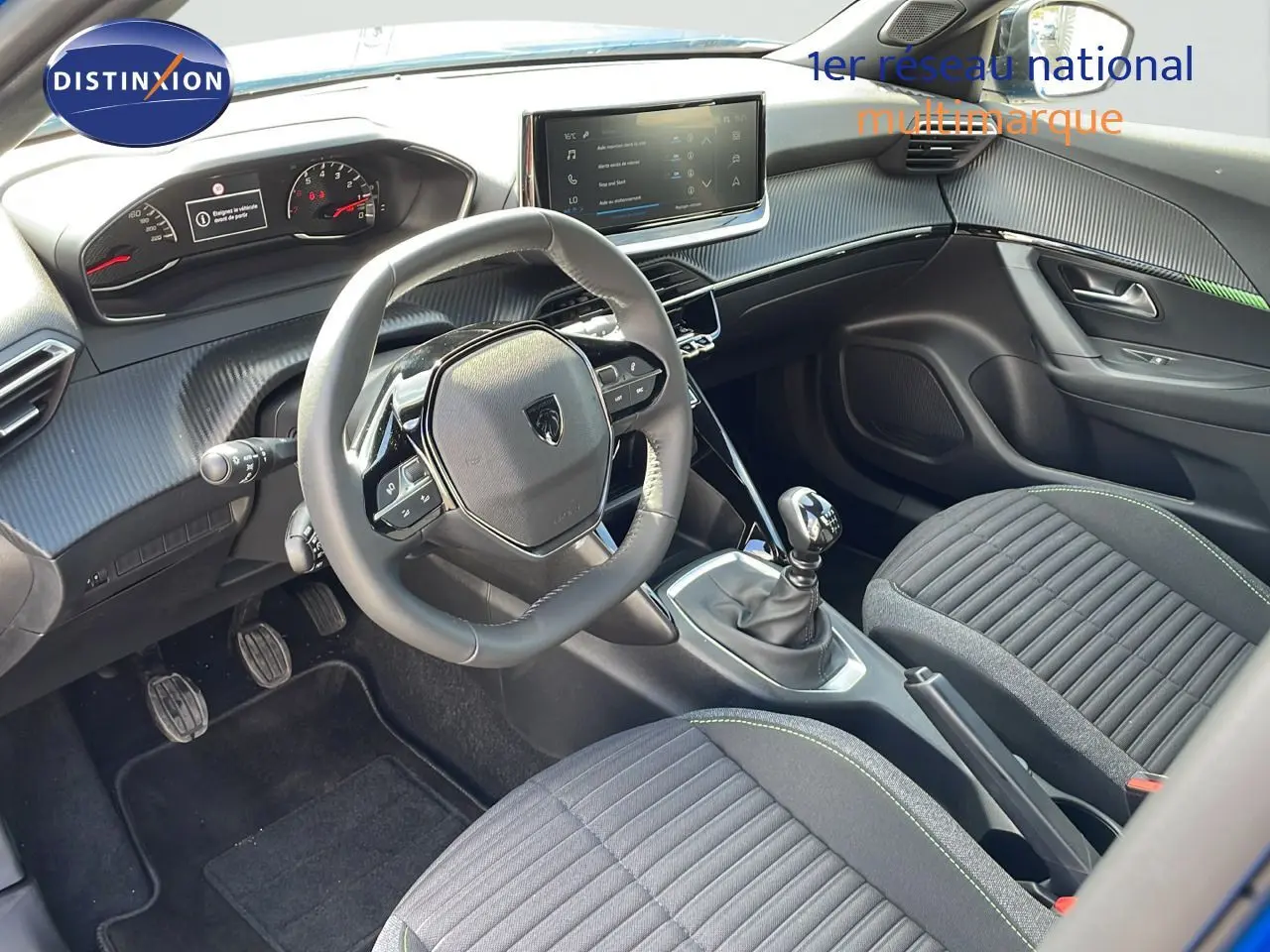 Vue intérieure côté conducteur du Peugeot 2008 2024, montrant le volant, la boîte manuelle et les sièges tissu noir avec surpiqûres vertes.