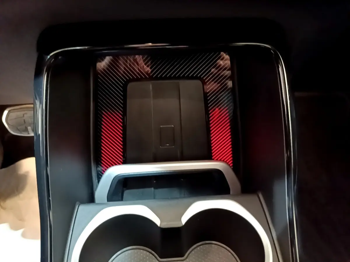Gros plan sur la console centrale noire avec porte-gobelets et surface à motifs rouges et noirs du BMW X1 xDrive23i M Sport.
