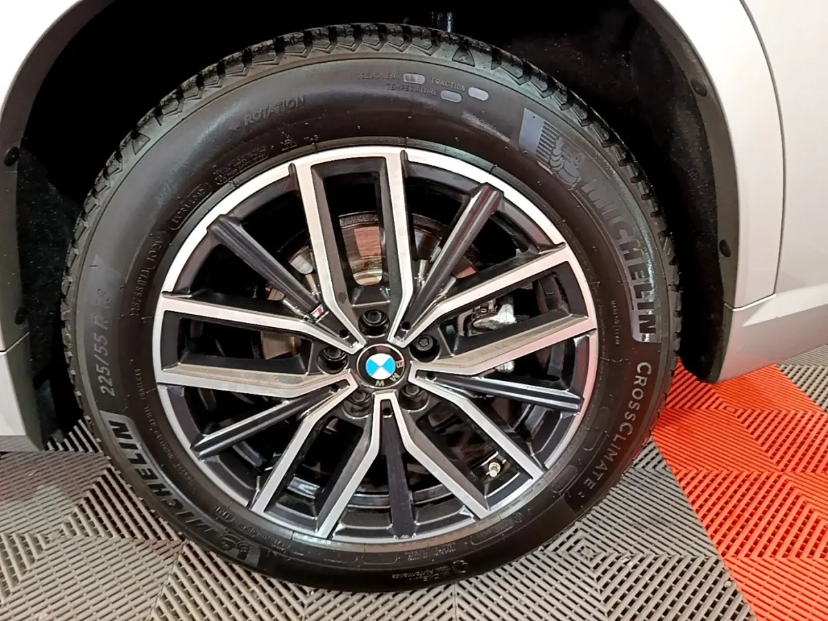 Gros plan sur la roue avant droite d’un BMW X1 gris clair avec jante alliage M Sport et pneu Michelin.
