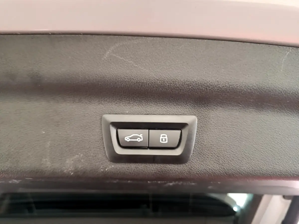 Boutons d'ouverture et de verrouillage du coffre sur la partie intérieure du hayon d'un BMW X1 gris clair 2023.