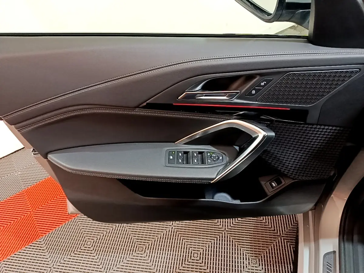 Vue intérieure du panneau de porte côté conducteur gris clair de BMW X1 xDrive23i M Sport 2023 avec commandes électriques et insert décoratif noir.