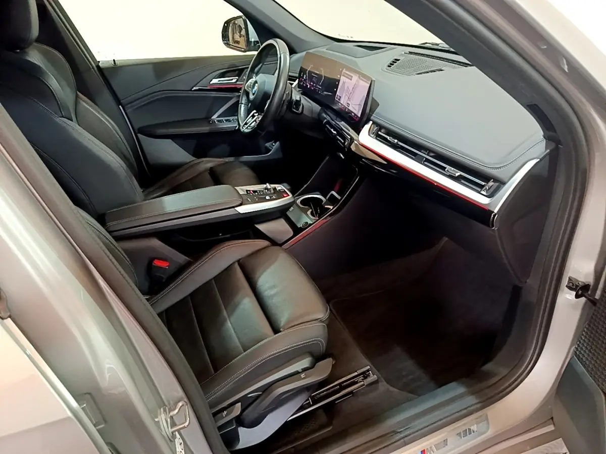 Vue intérieure côté conducteur du BMW X1 xDrive23i M Sport 2023, sièges cuir noirs et tableau de bord numérique.