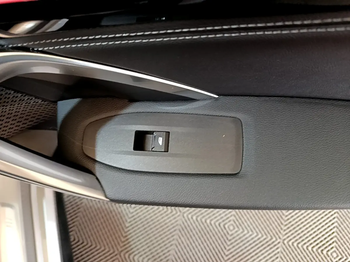Gros plan sur le bouton de commande de vitre électrique côté conducteur, intérieur noir du BMW X1 gris clair 2023.