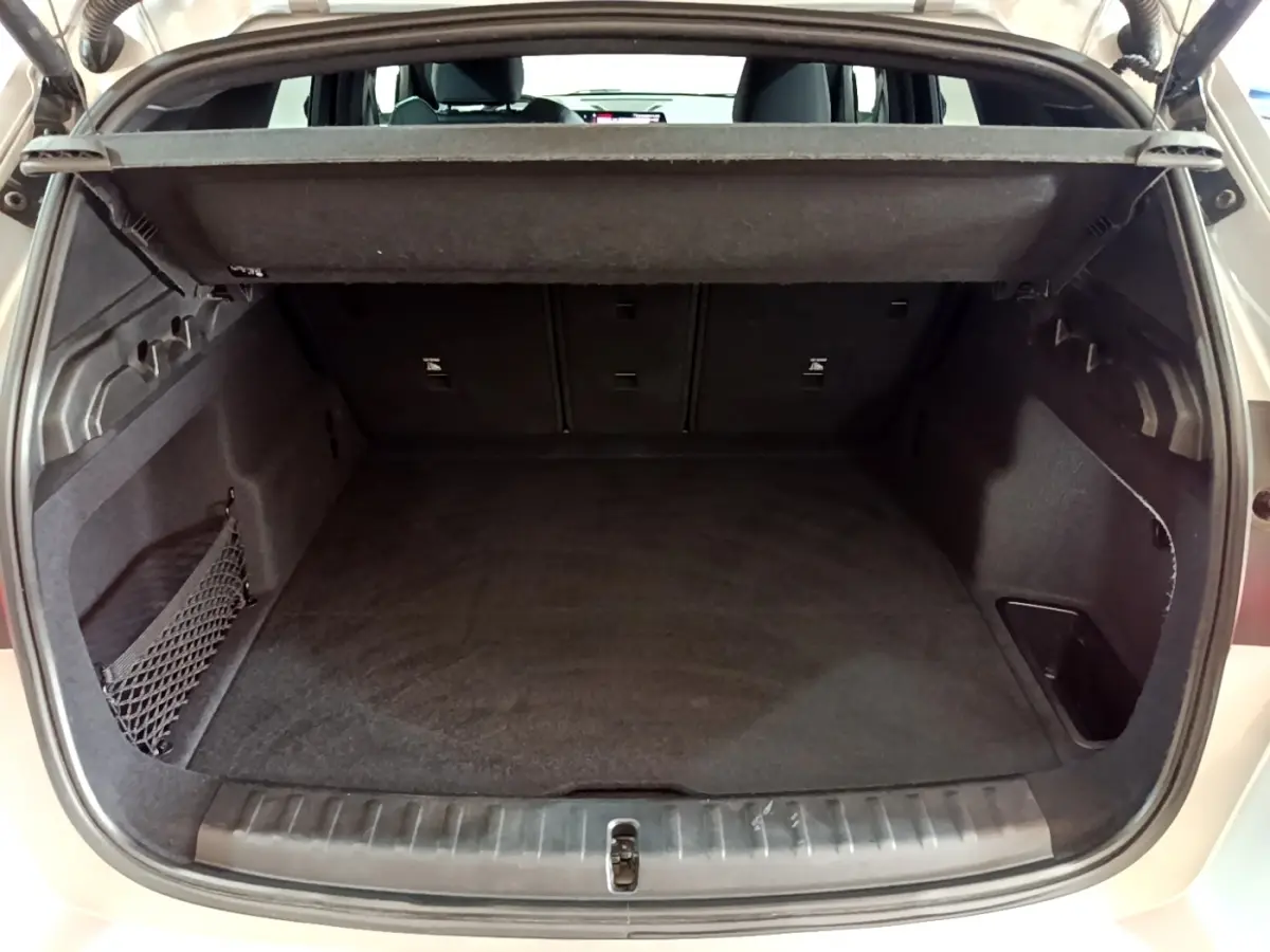 Coffre ouvert vu de l'arrière d'un BMW X1 gris clair, montrant un espace de chargement propre et bien agencé.