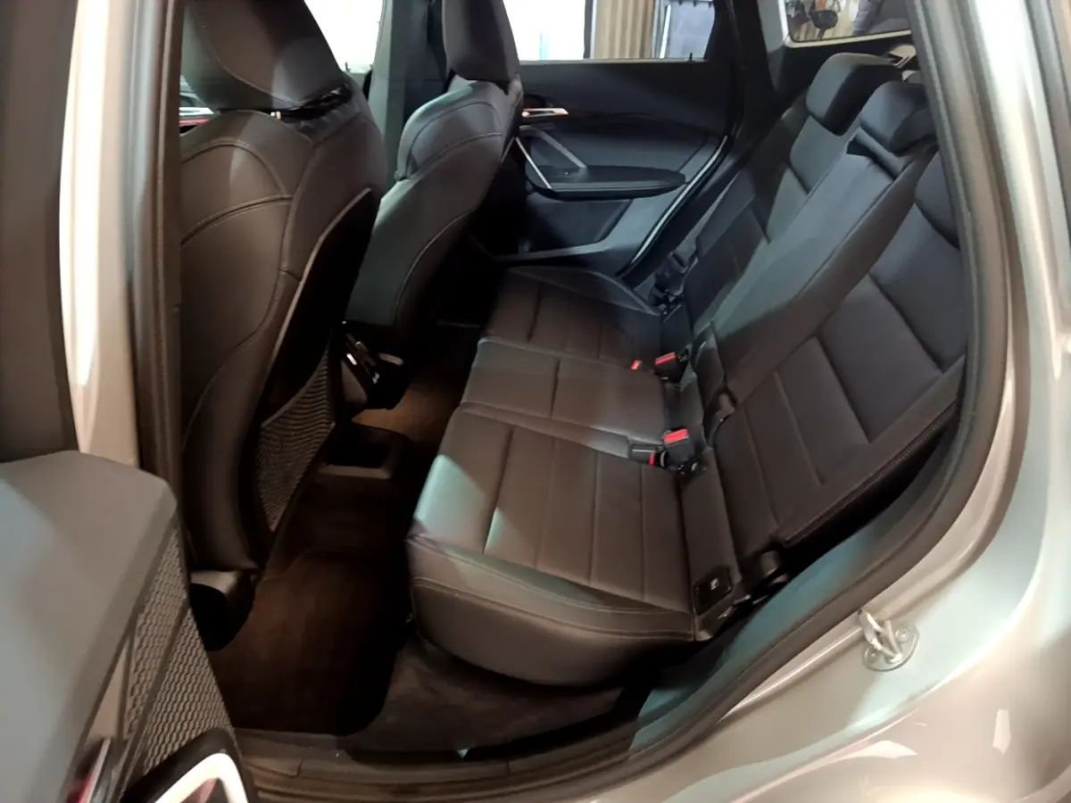 Vue intérieure côté droit montrant la banquette arrière en cuir noir du BMW X1 xDrive23i M Sport gris clair 2023.