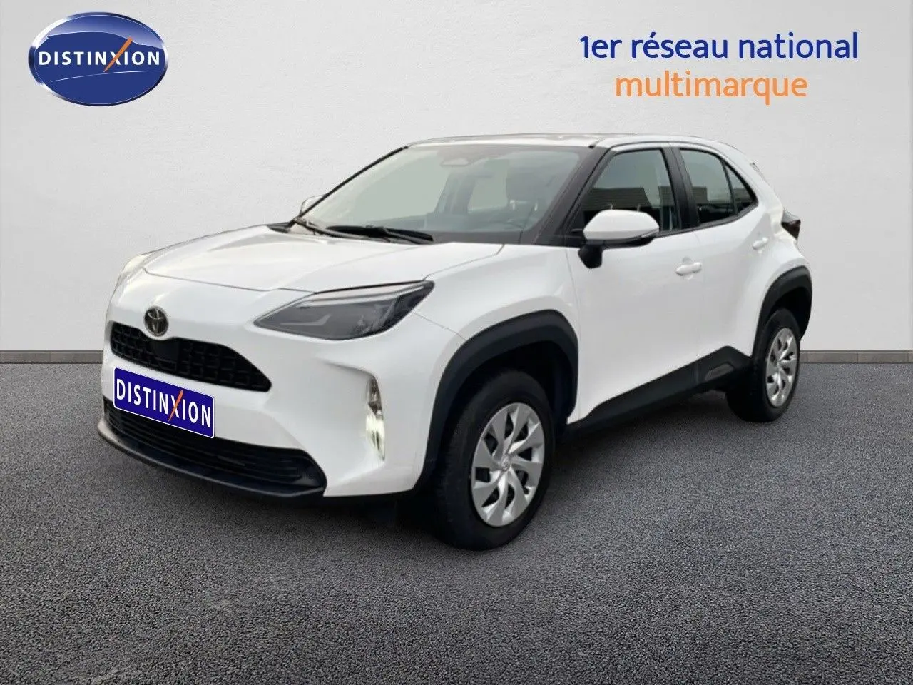 Toyota Yaris Cross blanc pur en 3/4 avant droit, avec calandre noire et protections d'ailes noires.