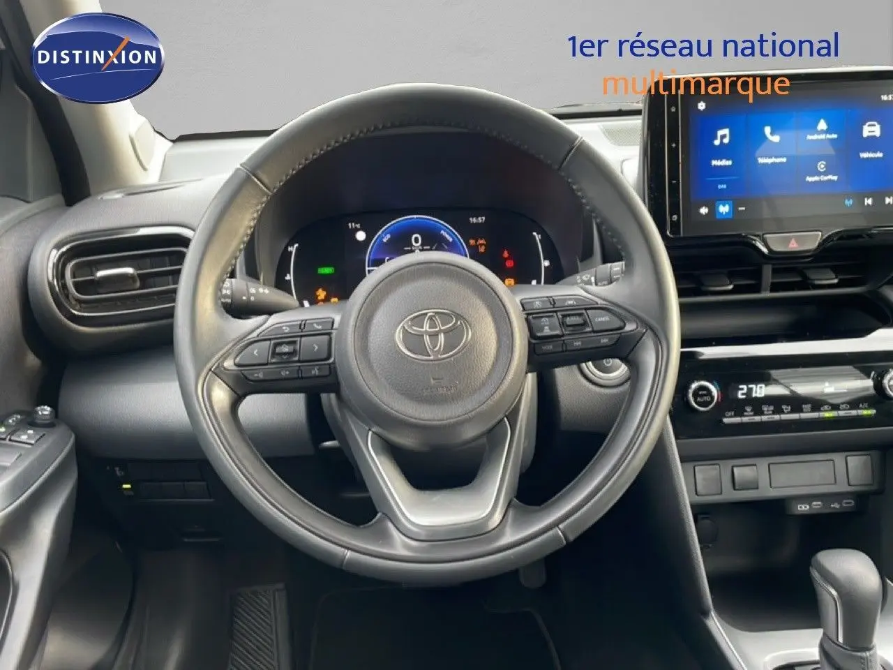 Vue intérieure centrée sur le volant cuir noir et le tableau de bord numérique de la Toyota Yaris Cross 2024.