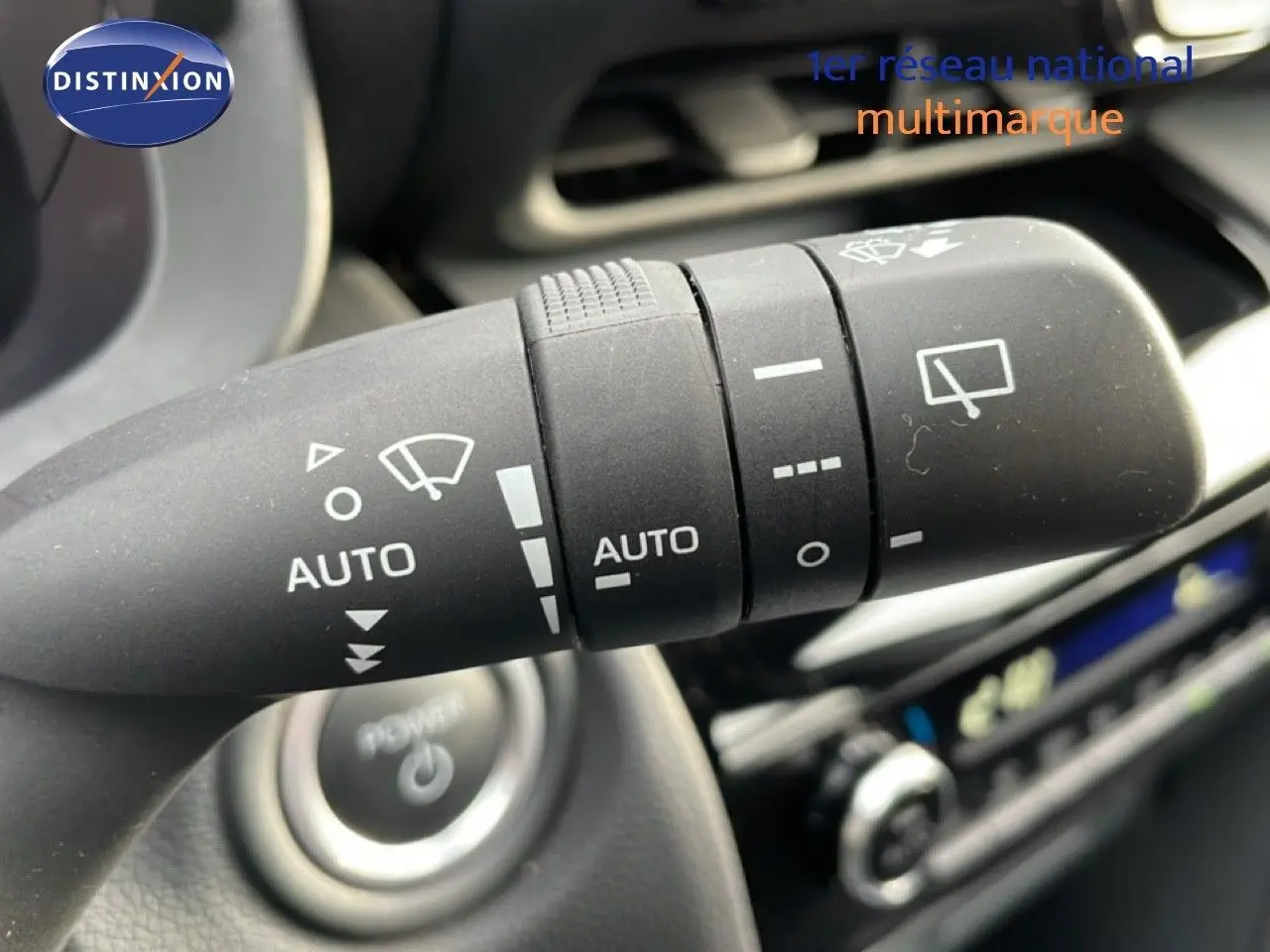 Gros plan sur la manette d’essuie-glace avec commandes automatiques dans l’habitacle d’une Toyota Yaris Cross blanche.