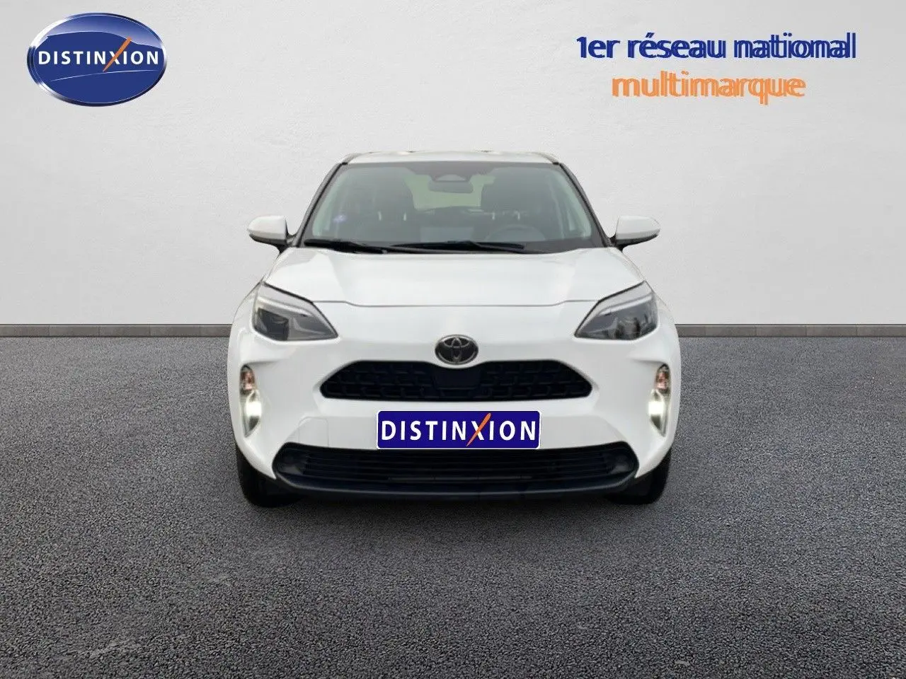 Vue frontale d'une Toyota Yaris Cross 1.5 Hybrid blanche, avec calandre noire et phares LED distinctifs.