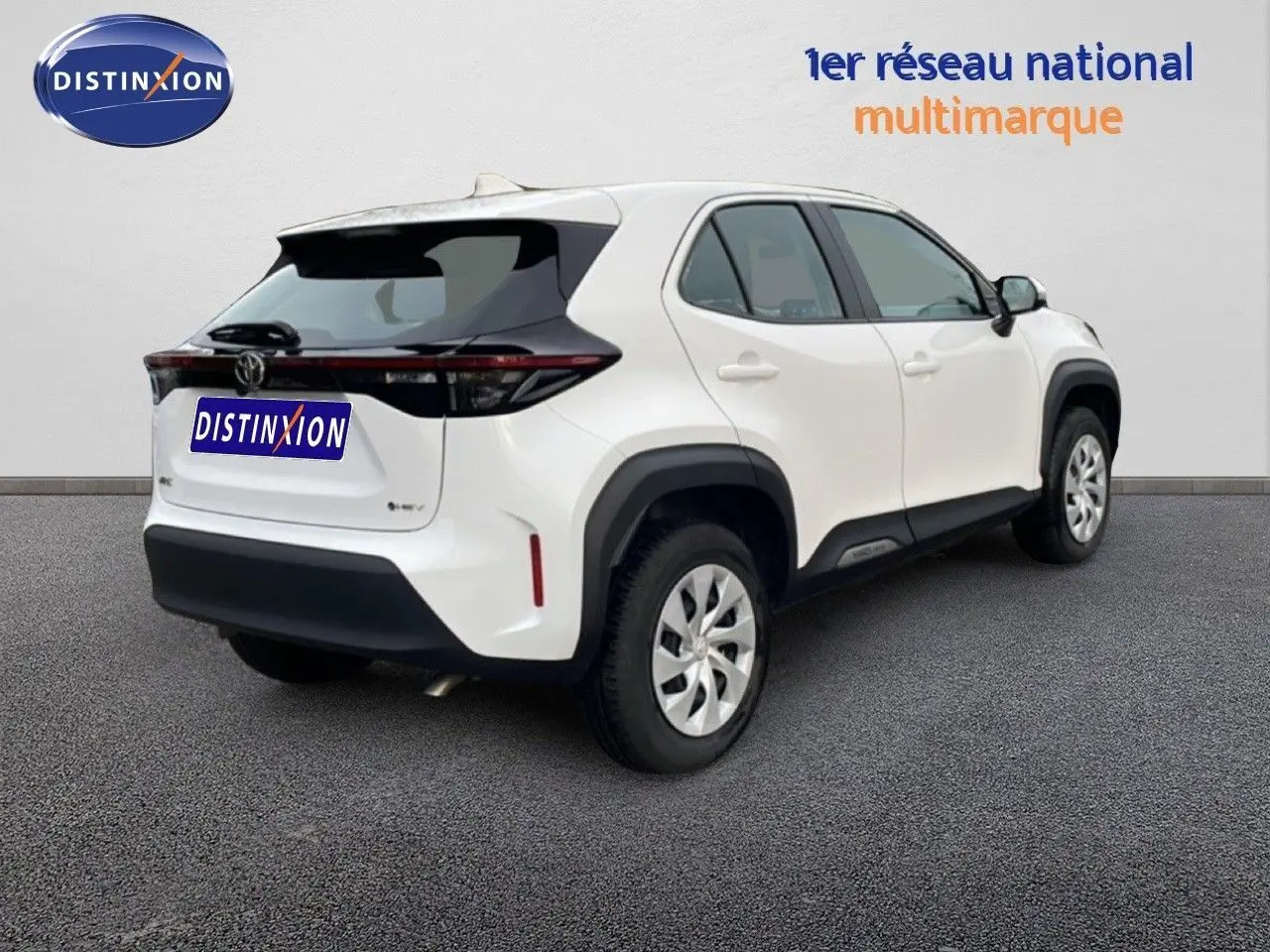 Vue 3/4 arrière droite d'une Toyota Yaris Cross blanche avec toit noir et feux arrière étirés en bandeau.