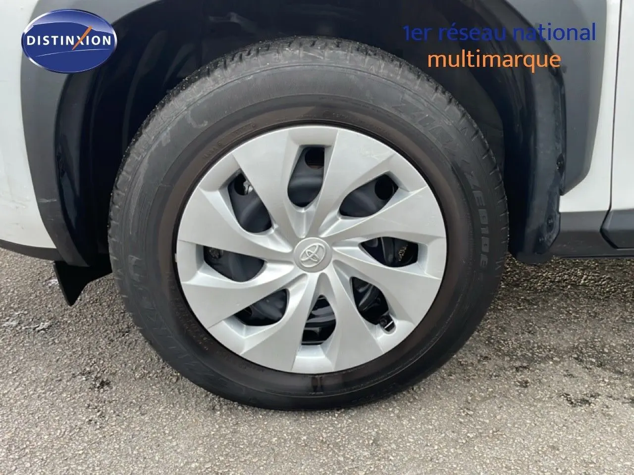 Gros plan sur la roue avant gauche blanche d'une Toyota Yaris Cross 2024 avec jante en plastique gris clair.