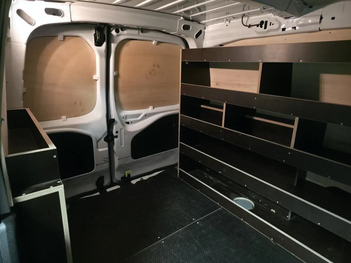 Vue intérieure arrière du Peugeot Partner blanc 2021 avec aménagements bois et plancher antidérapant noir.