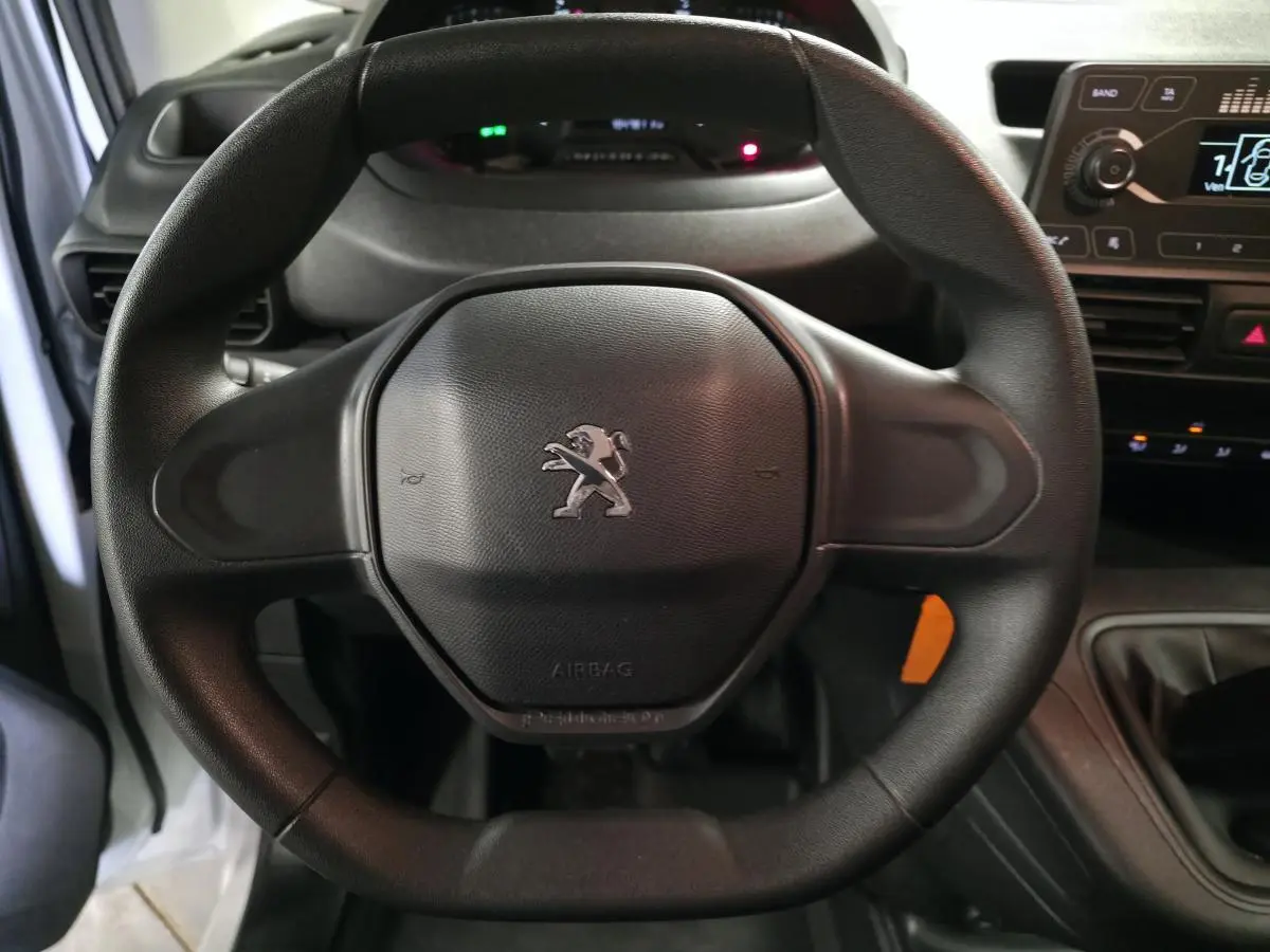 Gros plan sur le volant noir du Peugeot Partner 2021 avec logo lion au centre et tableau de bord en arrière-plan.