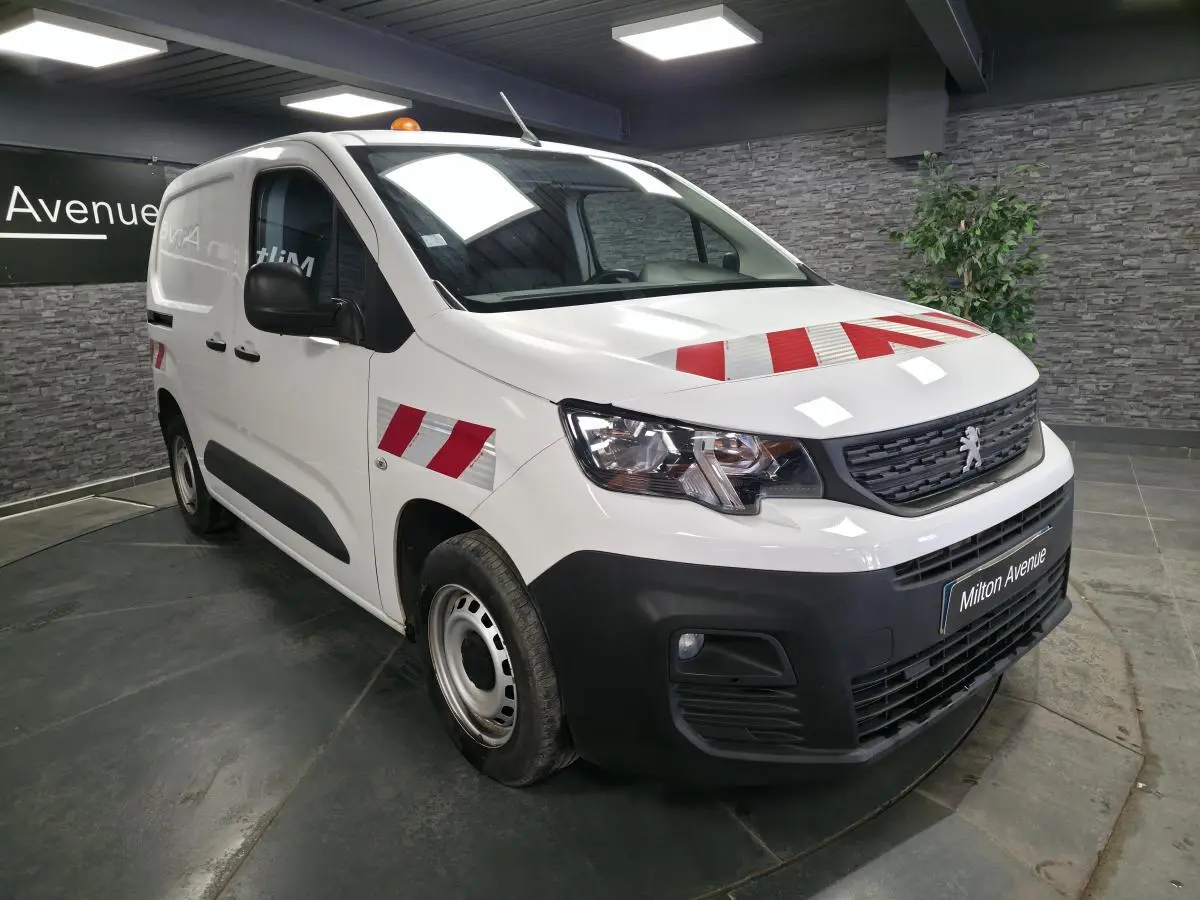 Peugeot Partner blanc vue 3/4 avant droit avec marquages rouges réfléchissants sur capot et ailes.