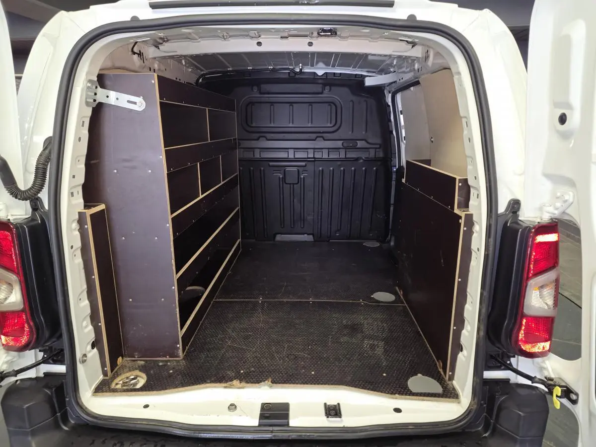 Vue arrière du Peugeot Partner blanc 2021 avec plancher et étagères bois dans la zone de chargement.