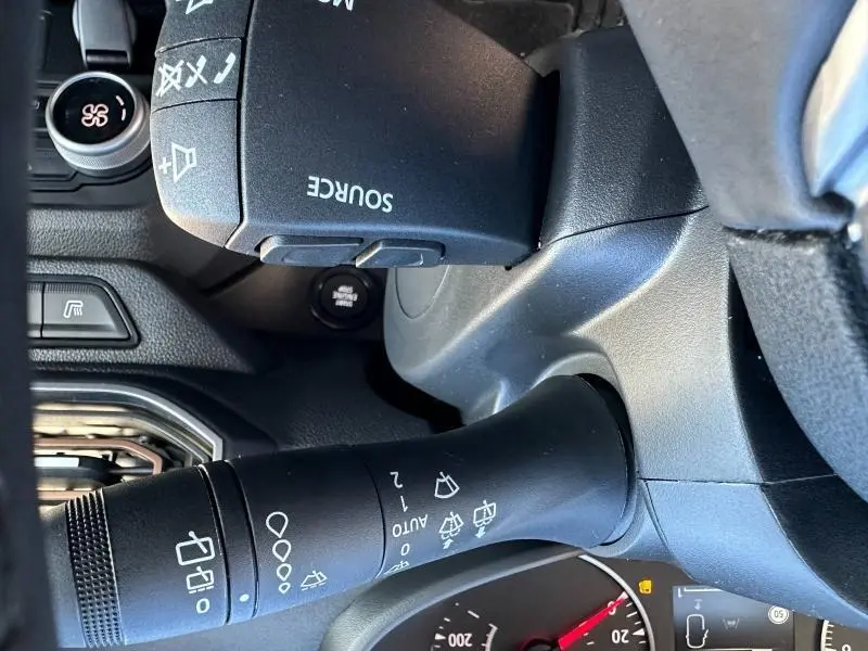 Gros plan sur la commande des essuie-glaces et le volant noir du Dacia Jogger blanc, intérieur côté conducteur.