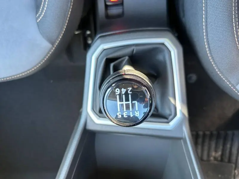 Gros plan sur le levier de vitesses manuel noir du Dacia Jogger blanc, entouré de la console centrale grise.