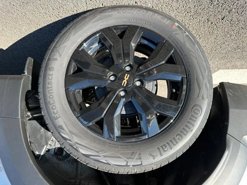 Gros plan sur la roue de secours noire avec jante alu brillante et logo DACIA au centre sur Dacia Jogger blanc.