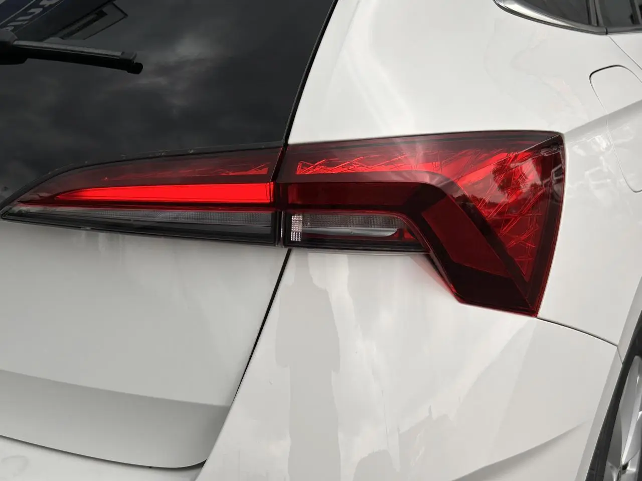 Gros plan sur le feu arrière droit d'une Skoda Scala 2025 blanc Candy avec lunette arrière surteintée.