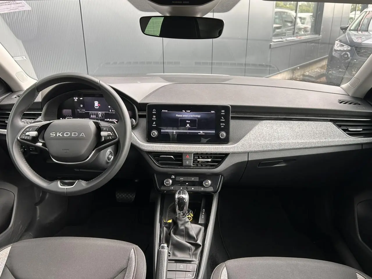 Vue intérieure frontale du poste de conduite de la Skoda Scala avec volant multifonctions et écran tactile central.