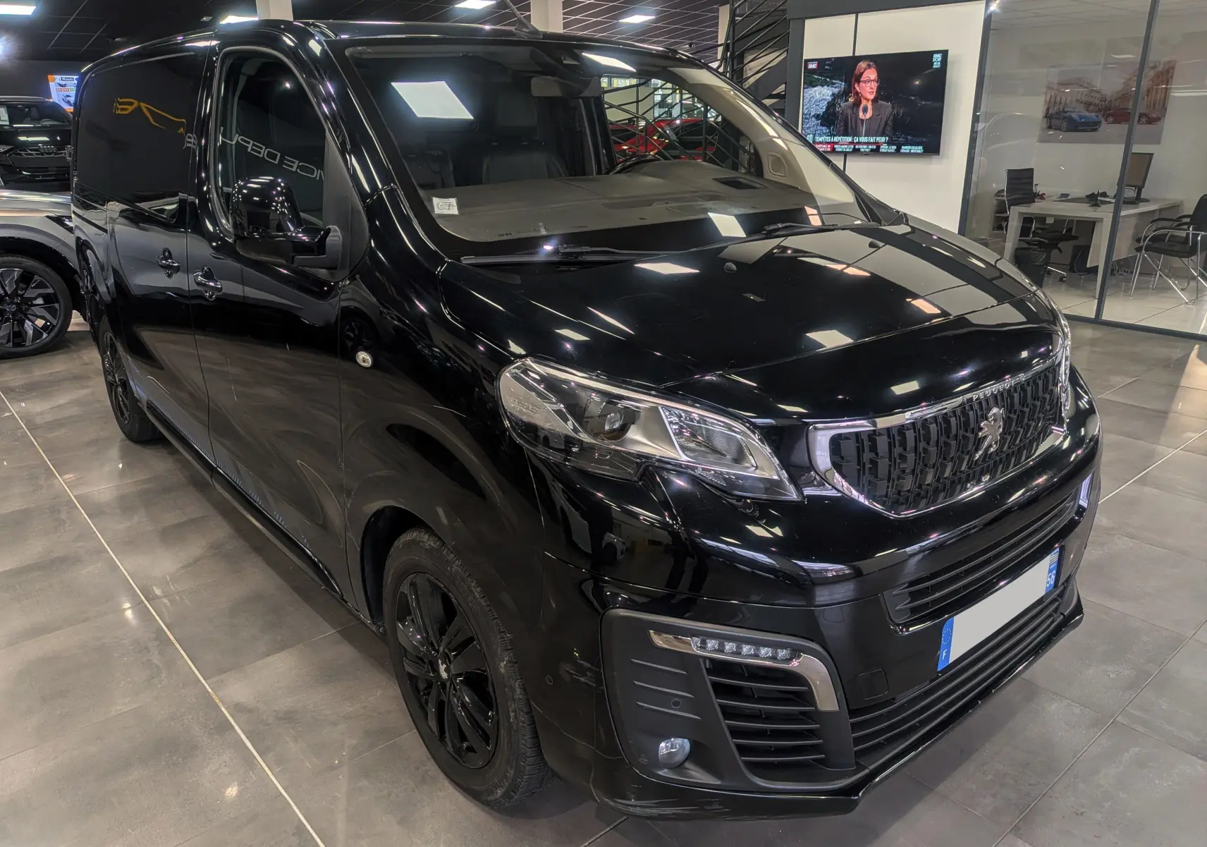 Vue 3/4 avant droit d’un Peugeot Expert Fourgon noir Perla avec calandre noire et jantes assorties en showroom.