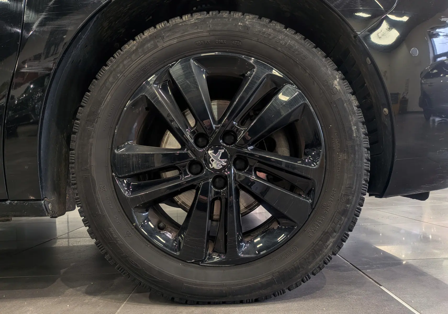 Gros plan sur la roue avant gauche noire Perla du Peugeot Expert Fourgon avec jante alliage noire brillante et logo Peugeot central.