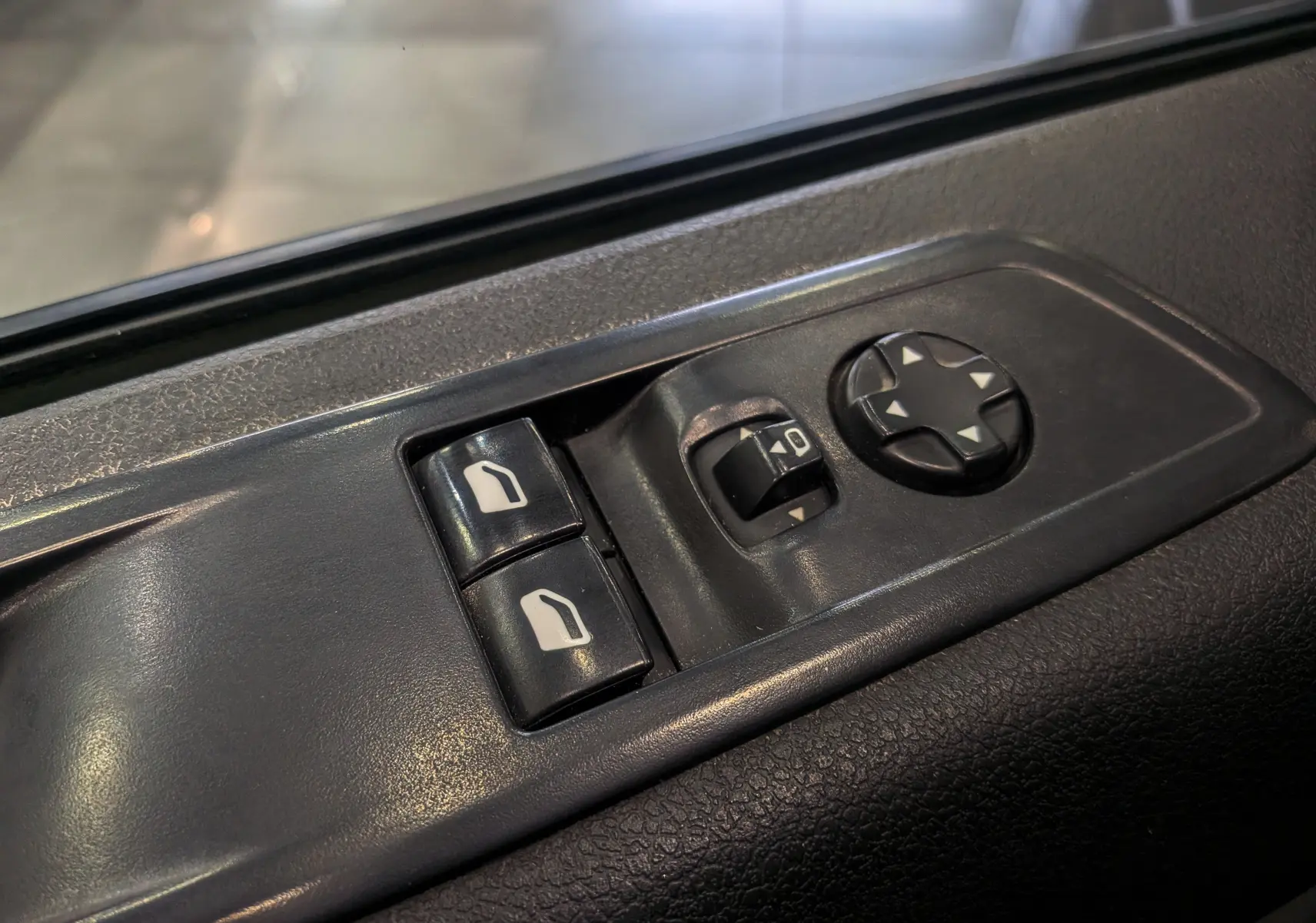 Gros plan sur les commandes de réglage des rétroviseurs et vitres côté conducteur du Peugeot Expert Fourgon noir Perla 2020.