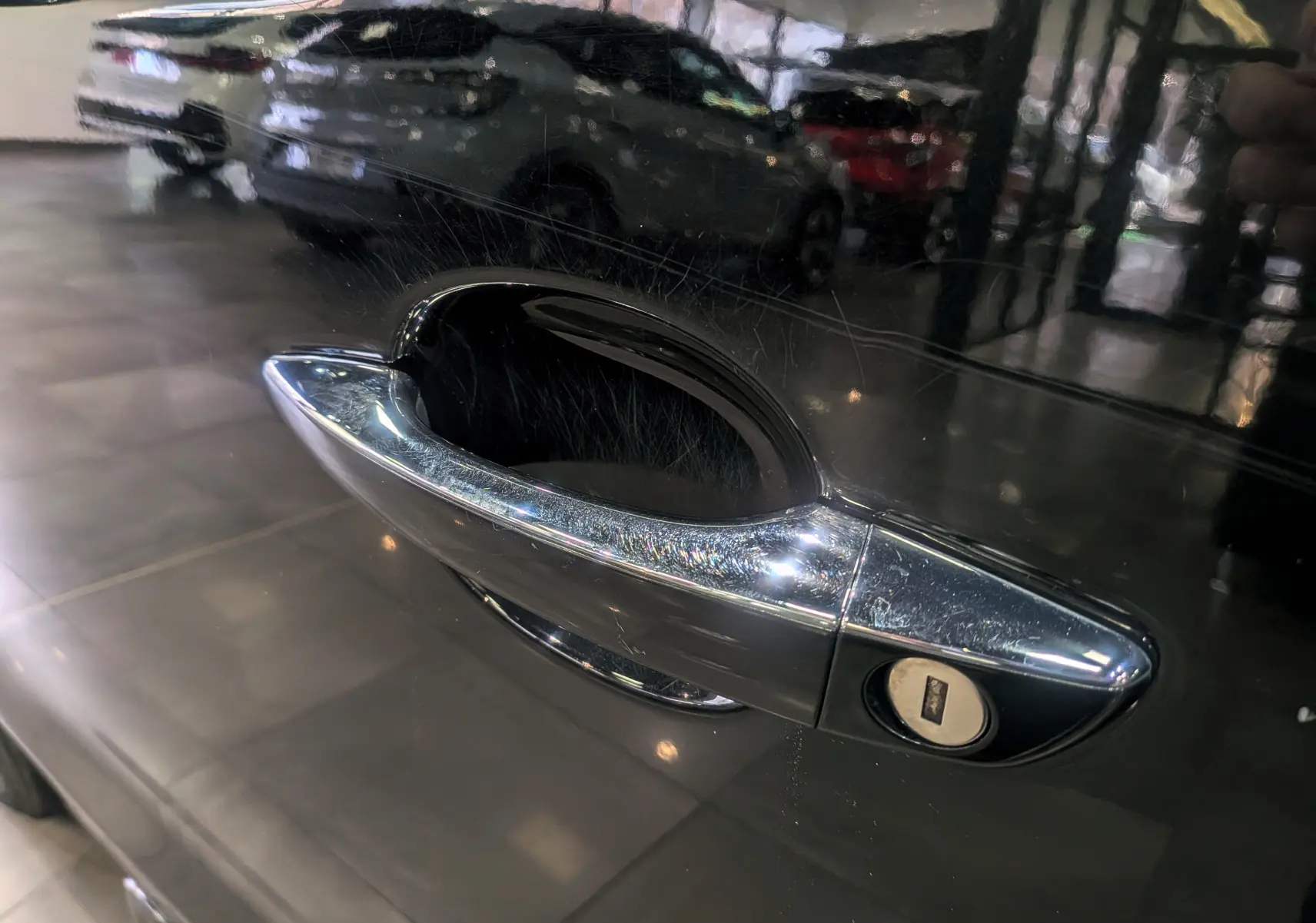 Poignée de porte chromée en gros plan sur la portière noire Perla d’un Peugeot Expert Fourgon 2020.