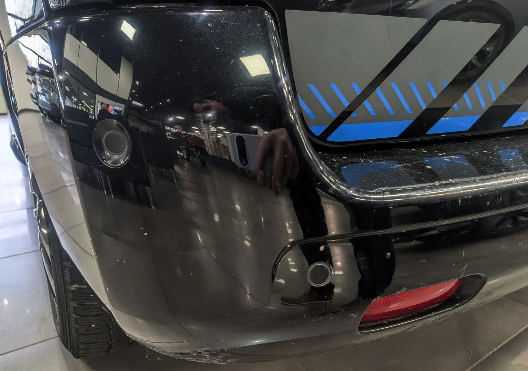 Gros plan sur le coin arrière gauche noir Perla du Peugeot Expert Fourgon, avec capteur de recul et feu rouge visible.