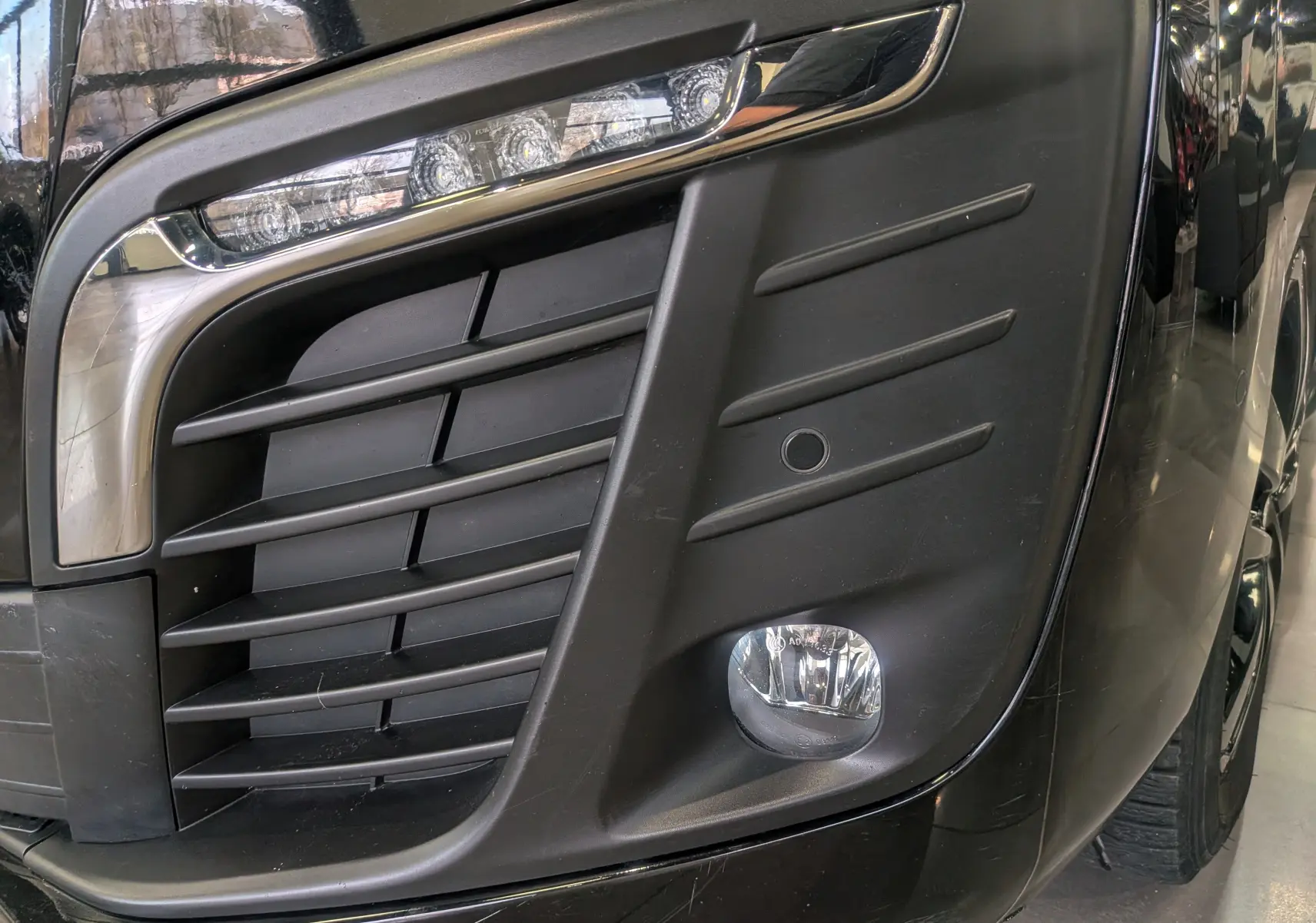 Gros plan sur le phare avant droit et la calandre noire du Peugeot Expert Fourgon Standard BlueHDi 180 de 2020.