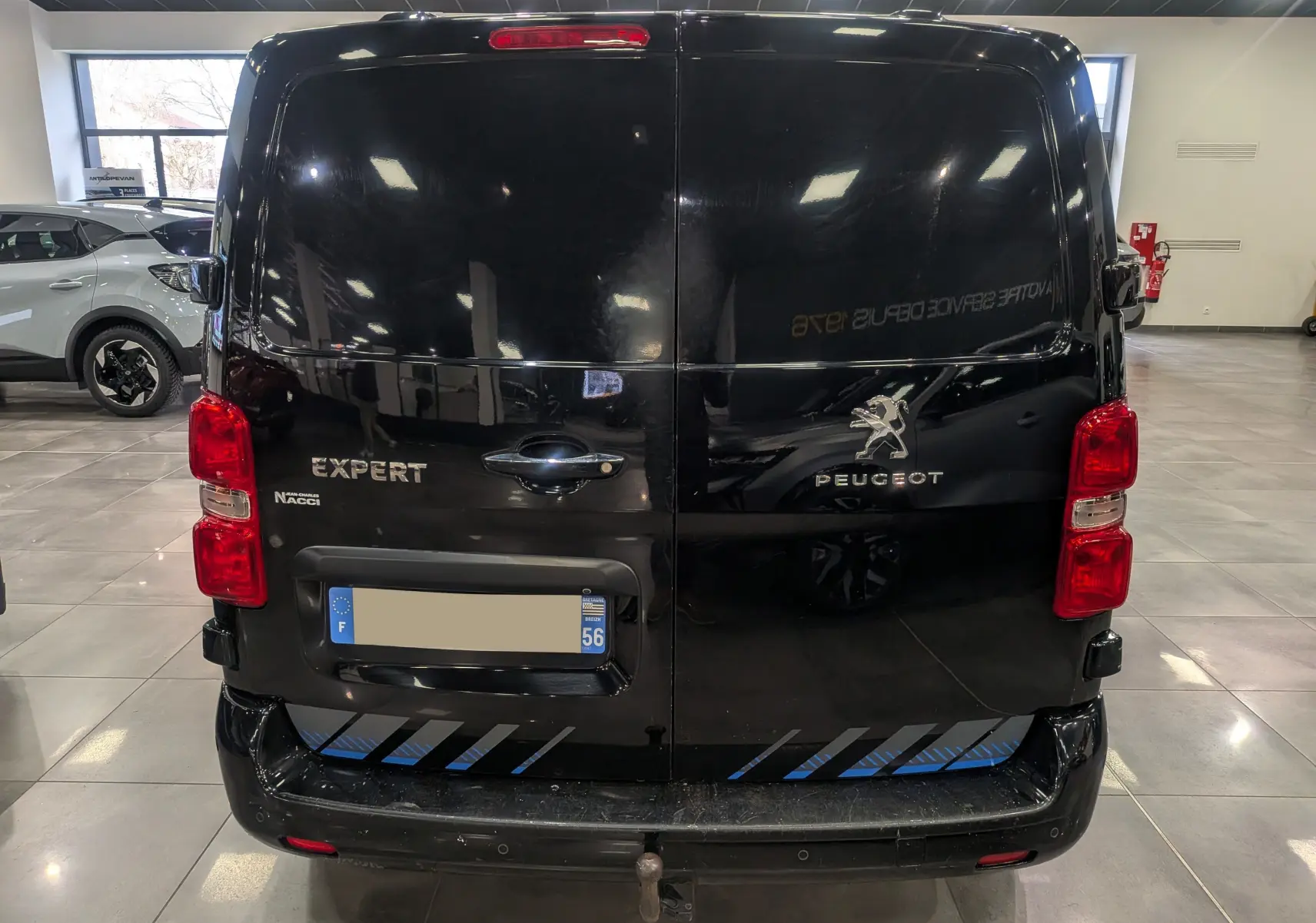 Vue arrière du Peugeot Expert Fourgon noir Perla, avec portes battantes fermées et feux rouges visibles en intérieur showroom.