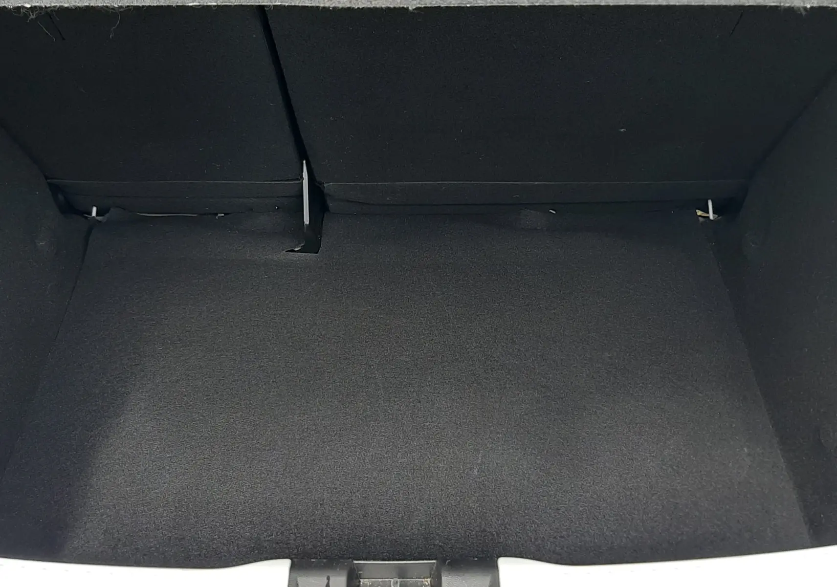 Coffre ouvert vu de face d'une Dacia Sandero blanc glacier 2024, espace de chargement vide et tapis noir.