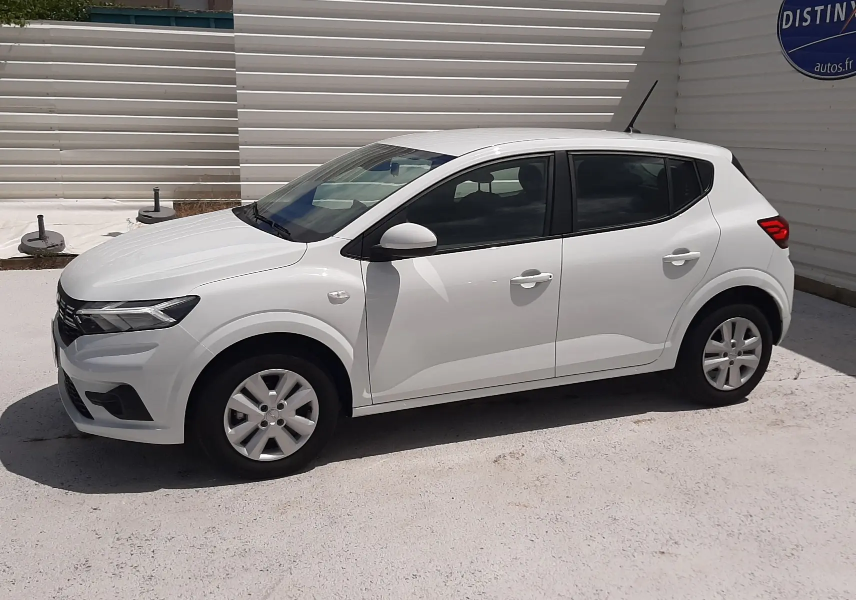 Vue latérale droite d'une Dacia Sandero blanc glacier 2024, compacte cinq portes avec jantes simples et vitres teintées.