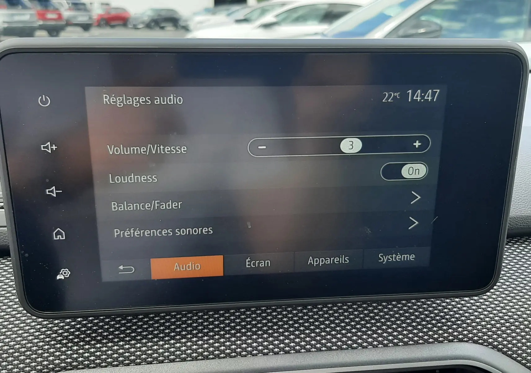 Écran tactile central affichant les réglages audio, avec tableau de bord texturé gris et aérateurs hexagonaux.