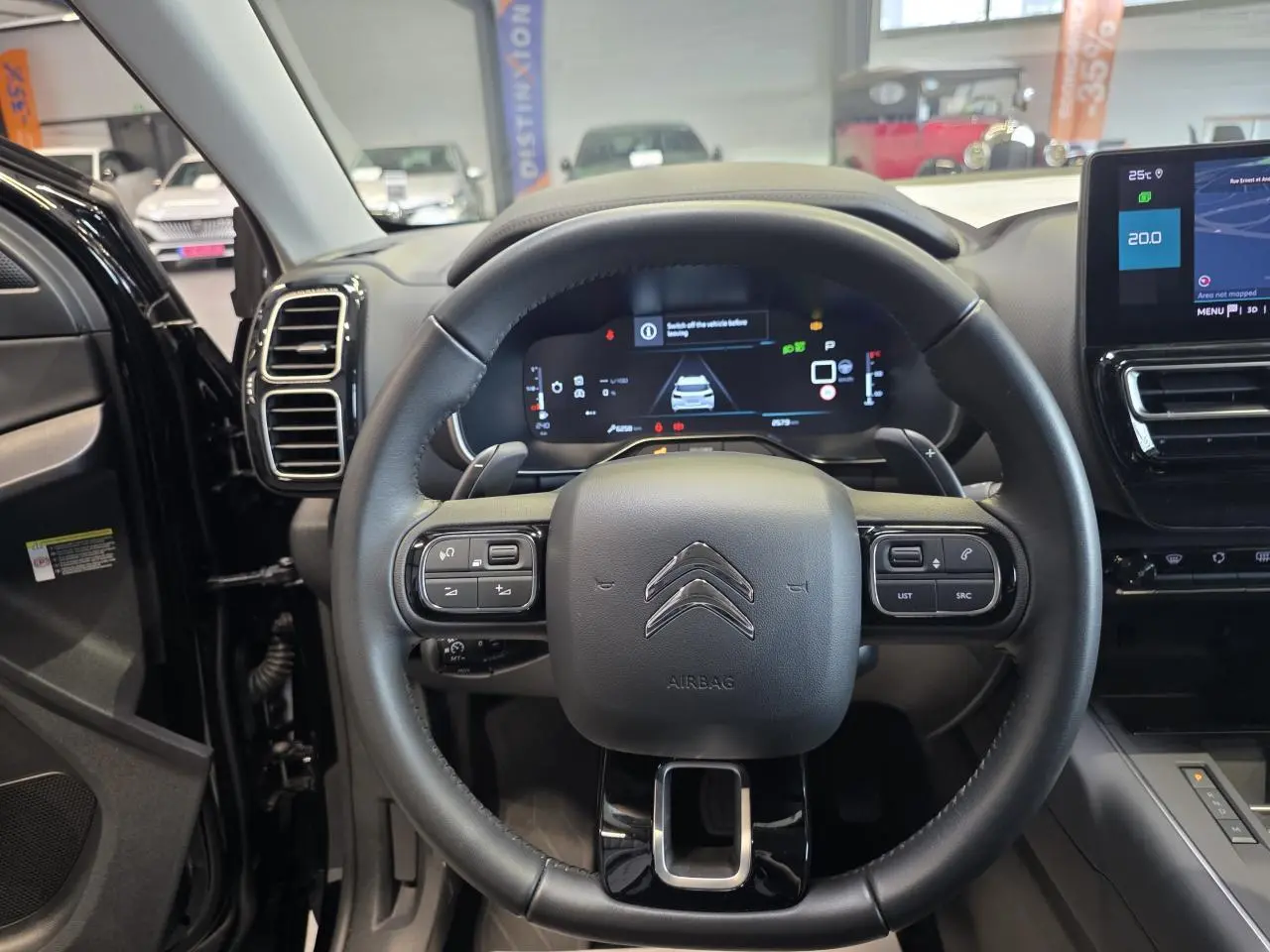 Vue intérieure centrée sur le volant noir du Citroën C5 Aircross 2025 avec tableau de bord numérique et écran tactile.