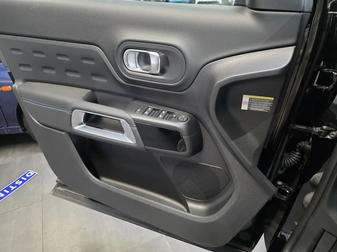 Vue intérieure côté gauche de la porte noire métallisée du Citroën C5 Aircross avec commandes de vitres et poignée argentée.