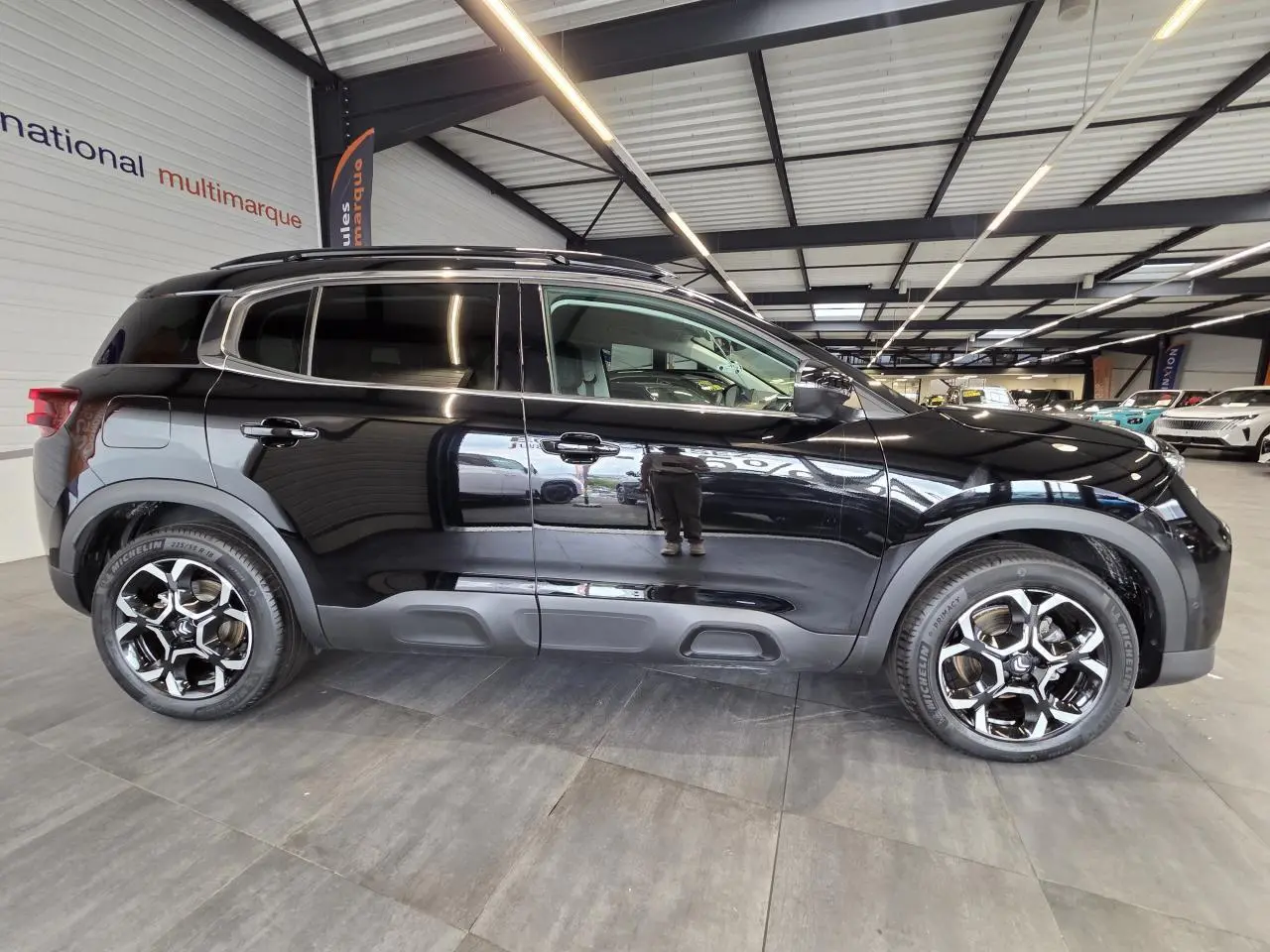 Profil droit d'un Citroën C5 Aircross noir métal 2025 avec jantes alliage bi-ton et protections latérales grises.