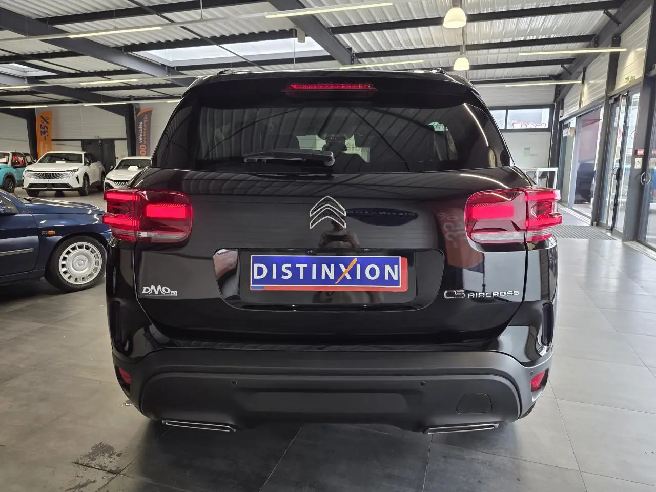Vue arrière d'un Citroën C5 Aircross noir métal avec feux arrière LED et double sortie d'échappement visible en showroom.