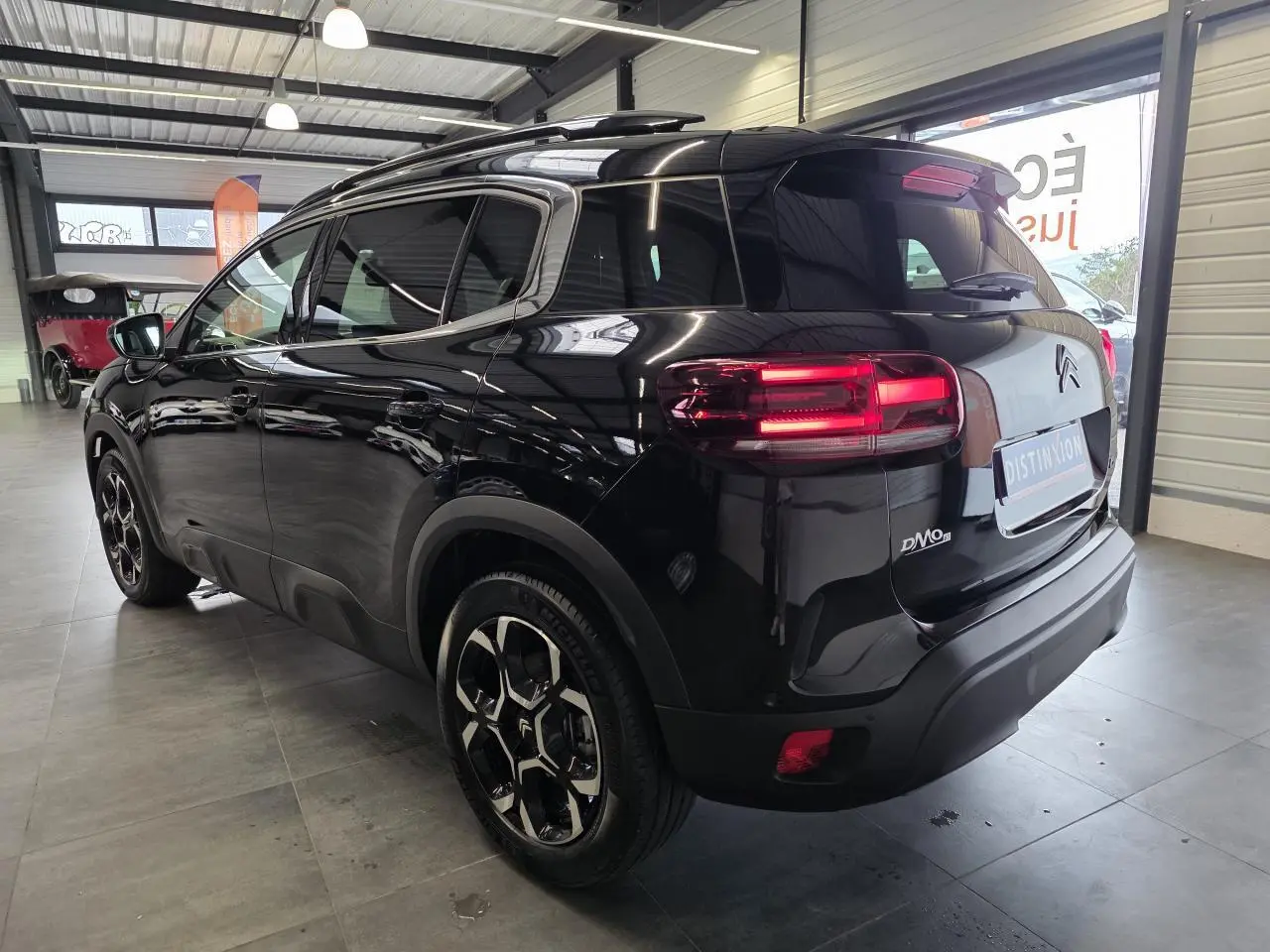 Vue 3/4 arrière droite du Citroën C5 Aircross noir métal avec jantes alliage et feux arrière LED allumés.